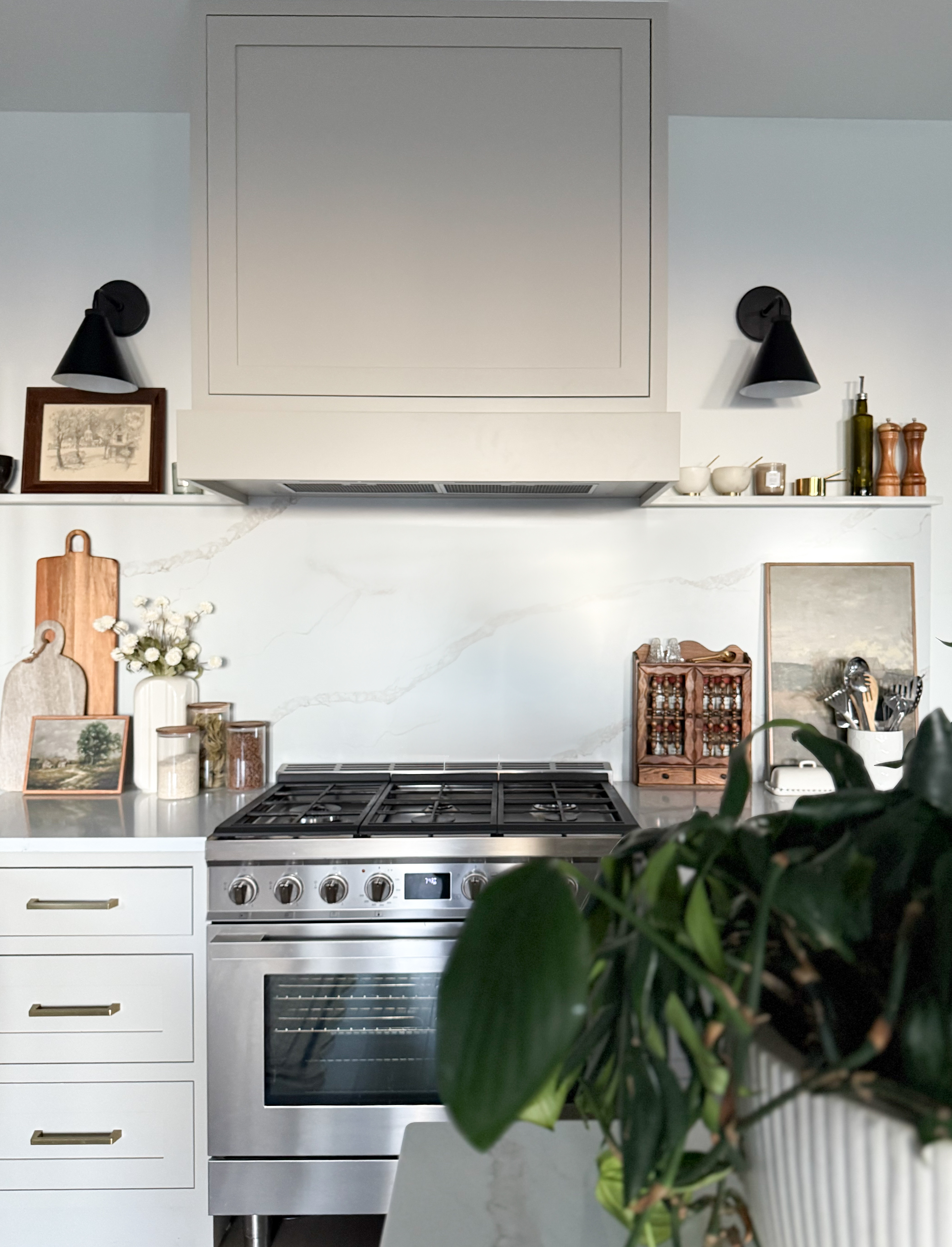 Modern kitchen with custom vent hood, white slab backsplash, and matte black sconces